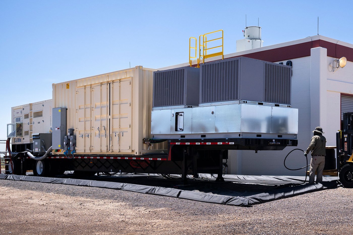 Kevin Cross connecting power from a trailer-mounted mobile power and cooling unit to six-degree-of-freedom shakers at Sandia National Laboratories